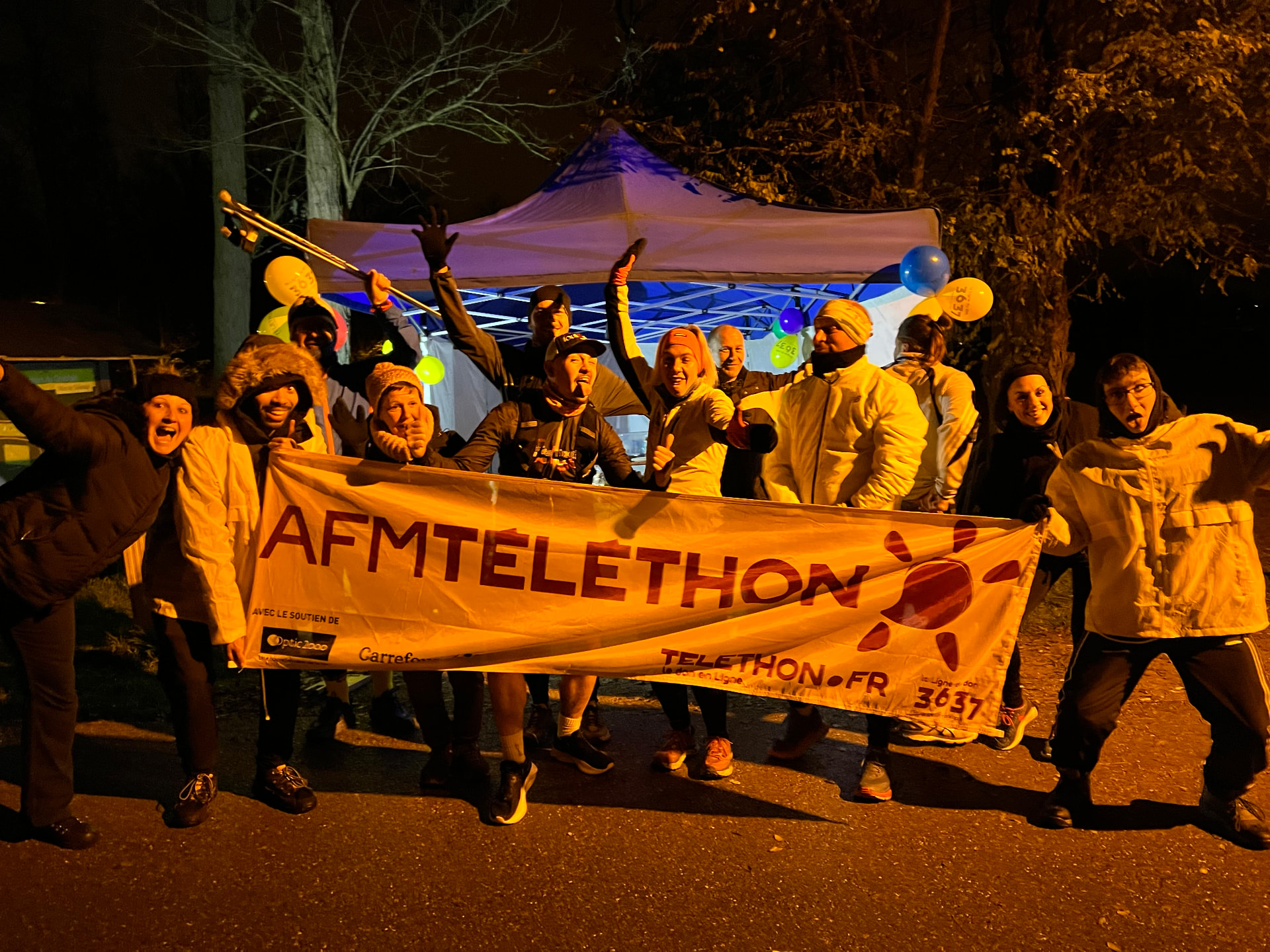 Bénévoles et participants derrière la banderole du Téléthon lors de l'édition 2022